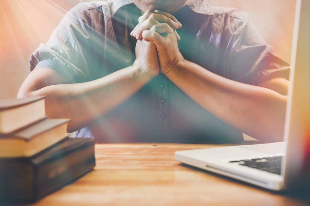 picture of a pastor praying next to computer
